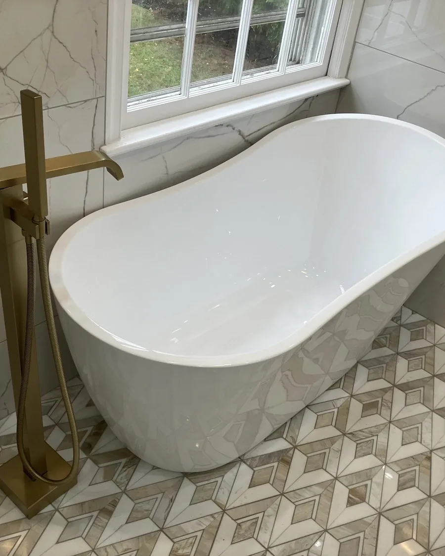 Freestanding tub with a brushed gold filler under a window