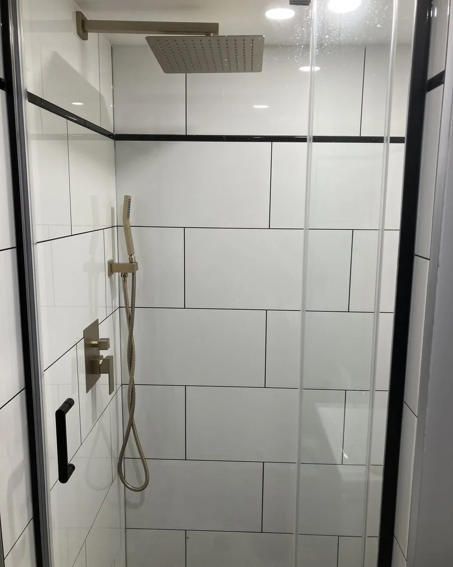 Walk-in shower in large format white tile with gold fixtures